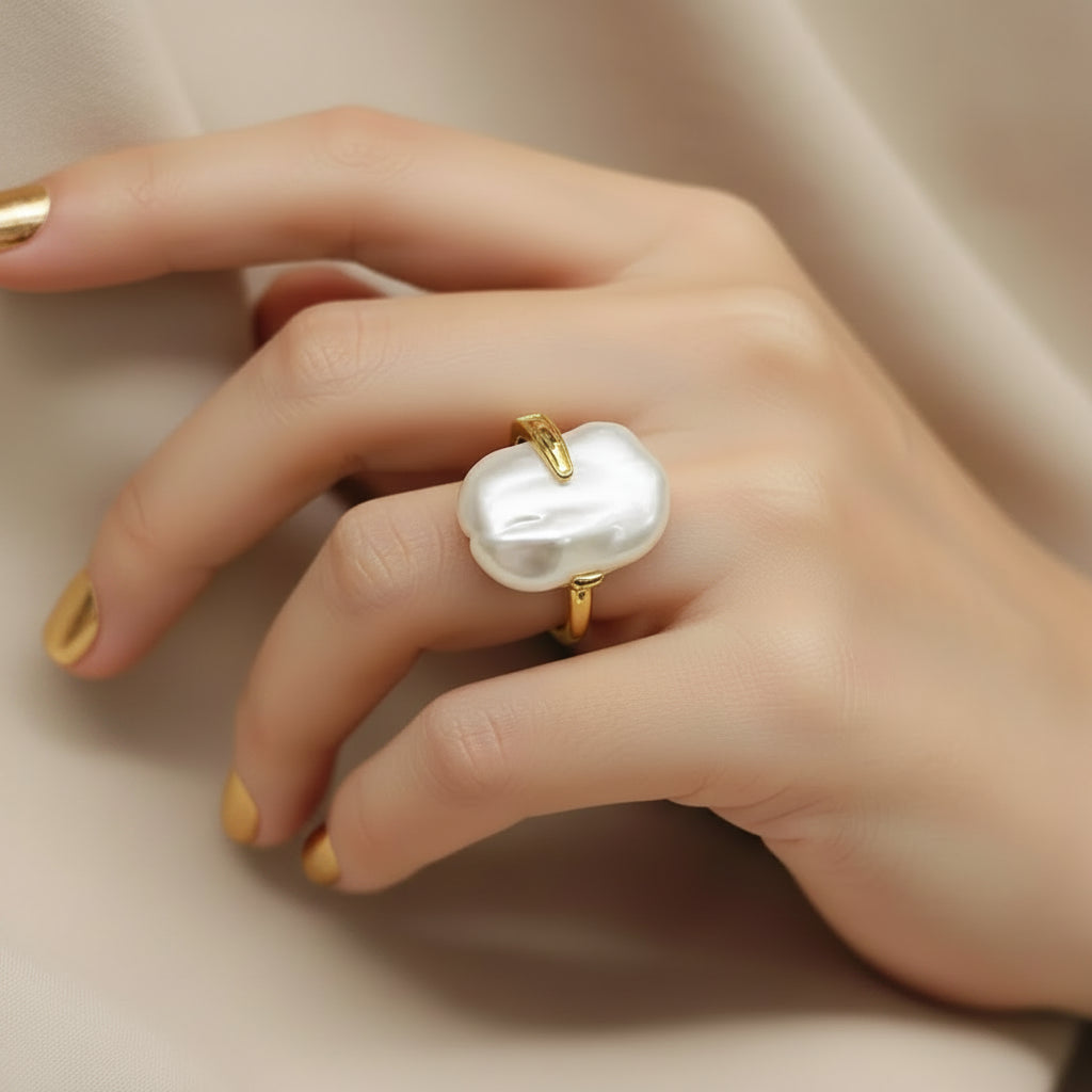 A baroque pearl ring with a gold band, displayed on a white jewelry card with gold trim. The brand name 'Dilati' is printed on the card.