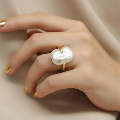 A baroque pearl ring with a gold band, displayed on a white jewelry card with gold trim. The brand name 'Dilati' is printed on the card.